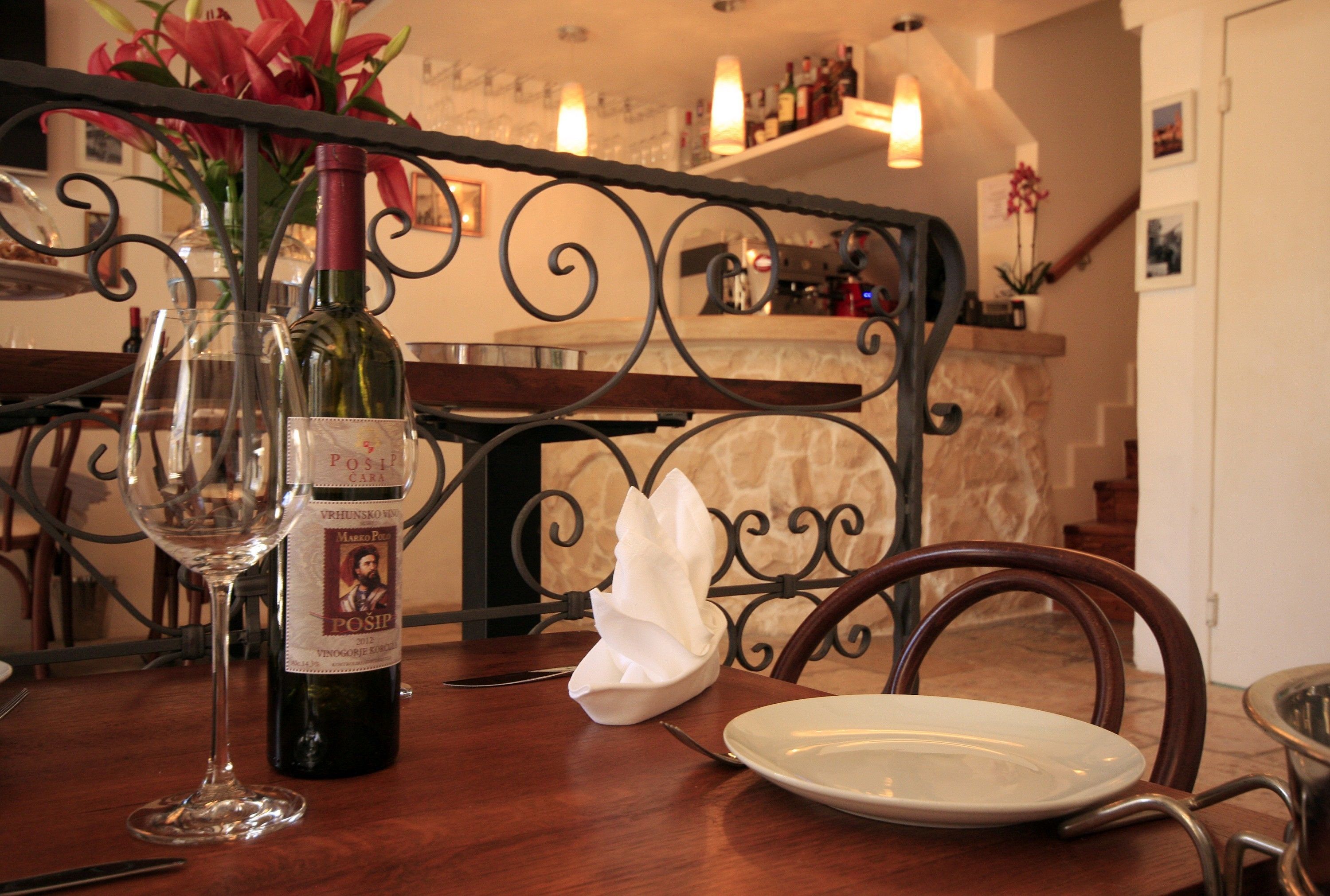 A dining table with a wine bottle, a glass, and a napkin.