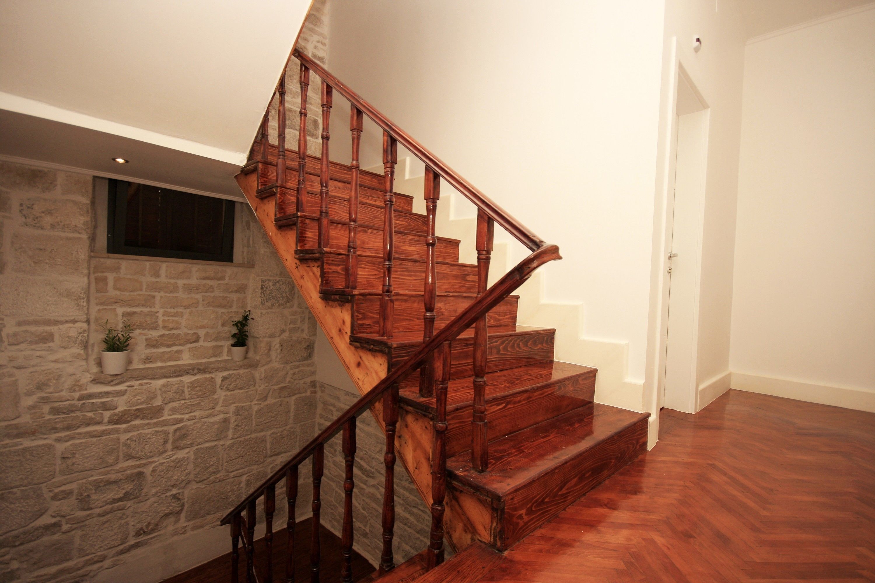 A wooden staircase with stone walls and potted plants.