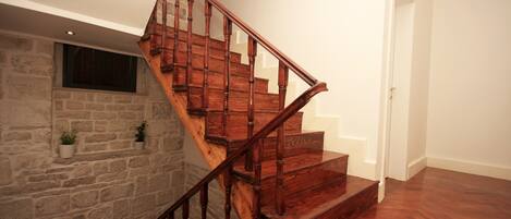 A wooden staircase with stone walls and potted plants.
