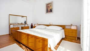 A bedroom with a wooden bed, white bedding, a large mirror, bedside tables, and a framed picture on the wall. - Apartment Ivo (Rovinj)