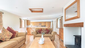 A cozy living room with a sofa set, a wooden coffee table, and a fireplace. - Hay Barn - Two Bedroom Cottage, Sleeps 5 (Saint Breock)