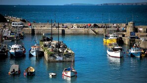 Un port où sont amarrés différents types de bateaux, une jetée animée par la présence de personnes, et une vue dégagée sur la mer.