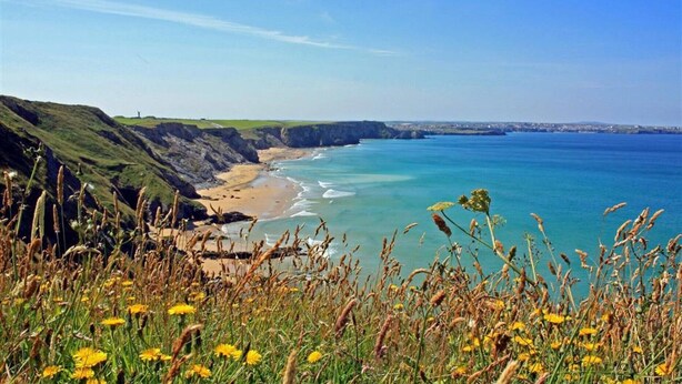 Un paysage côtier avec des falaises, une plage et une mer bleue et limpide.