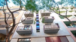 Un immeuble résidentiel à plusieurs étages, doté de balcons, d’une petite fenêtre et d’un volet rouge.