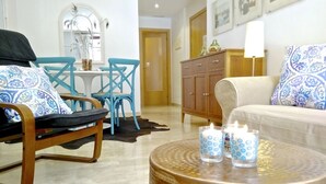 Un salon comprenant un canapé, un fauteuil, une petite table avec des bougies et un meuble.