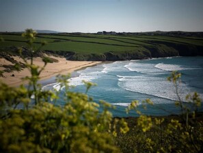 A coastal landscape with a beach, waves, and rolling hills. - Crab Cottage - Two Bedroom Cottage, Sleeps 3 (Mawgan Porth)