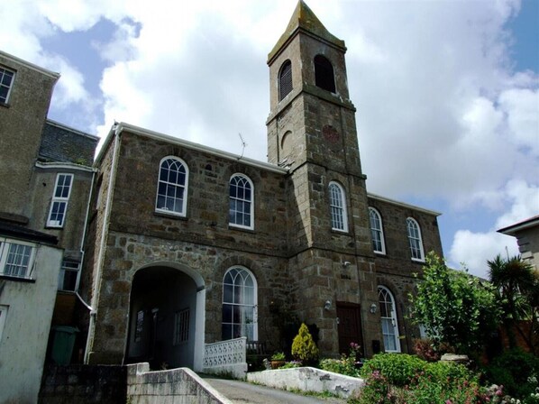 A historic stone building with a prominent tower, arched windows, and a central entrance.
