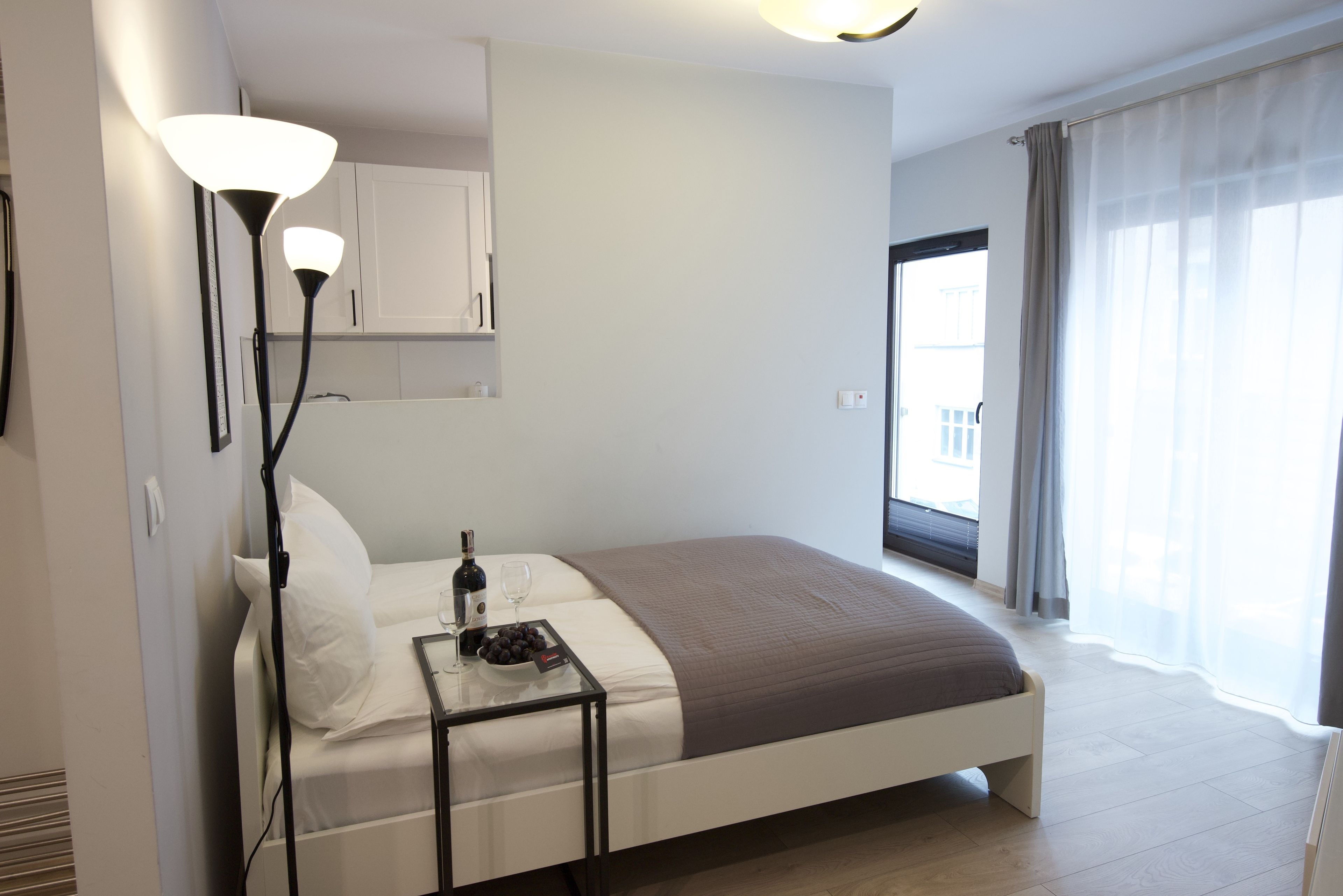 A modern hotel room with a bed, bedside table, and a large window with curtains.