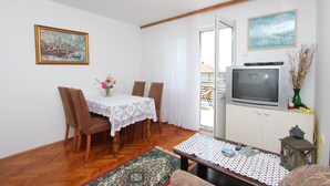 Una sala de estar con una mesa de comedor, sillas, un televisor y un sofá.