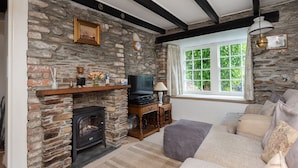 A cozy living room with a stone fireplace, a television, and a comfortable sofa.