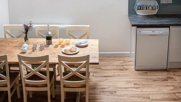 A modern kitchen with a skylight, wooden dining table, and hanging pendant lights. - The Organ Loft - Two Bedroom Cottage, Sleeps 4 (England)