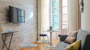 Un salon moderne comprenant un canapé, deux fauteuils, une petite table ronde et un téléviseur fixé au mur.