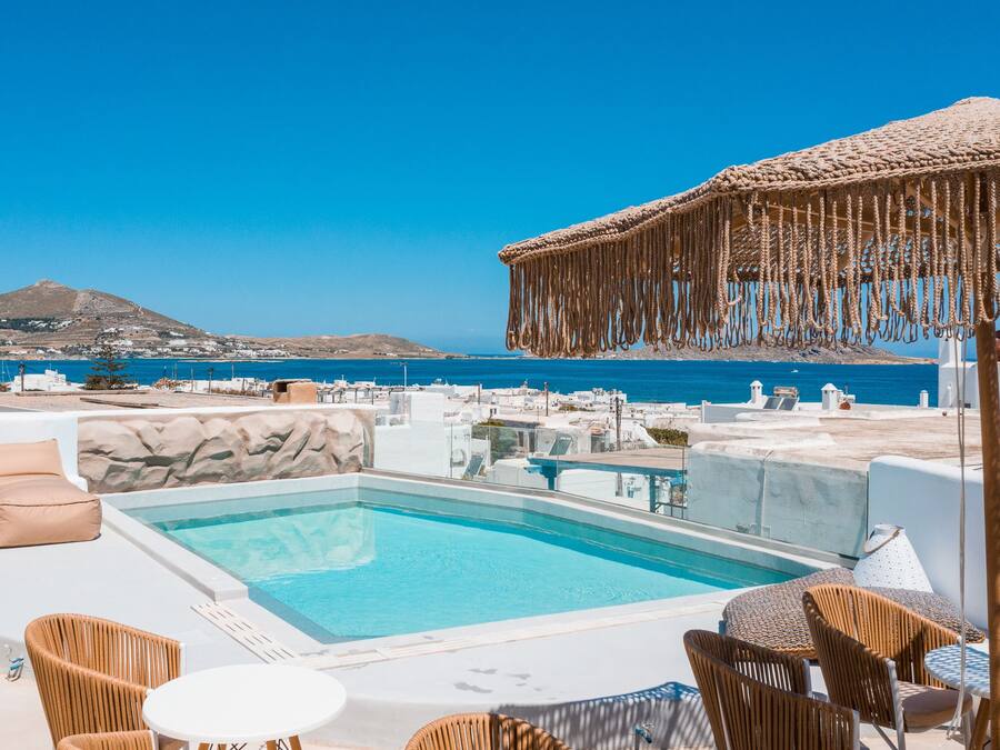 Zona de piscina en la azotea con vistas despejadas al mar y una montaña al fondo.