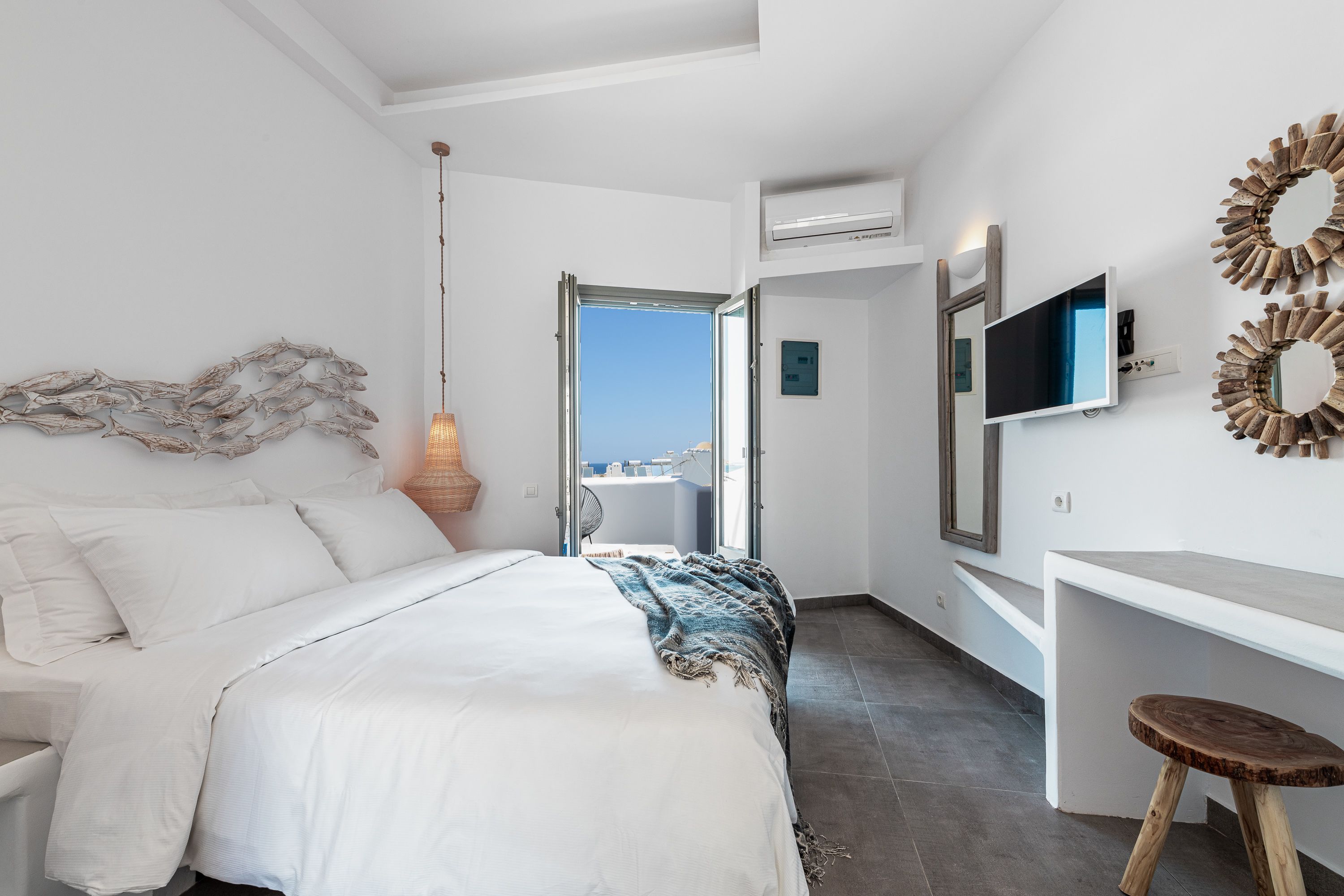 A modern bedroom with a bed, a desk, and a TV.