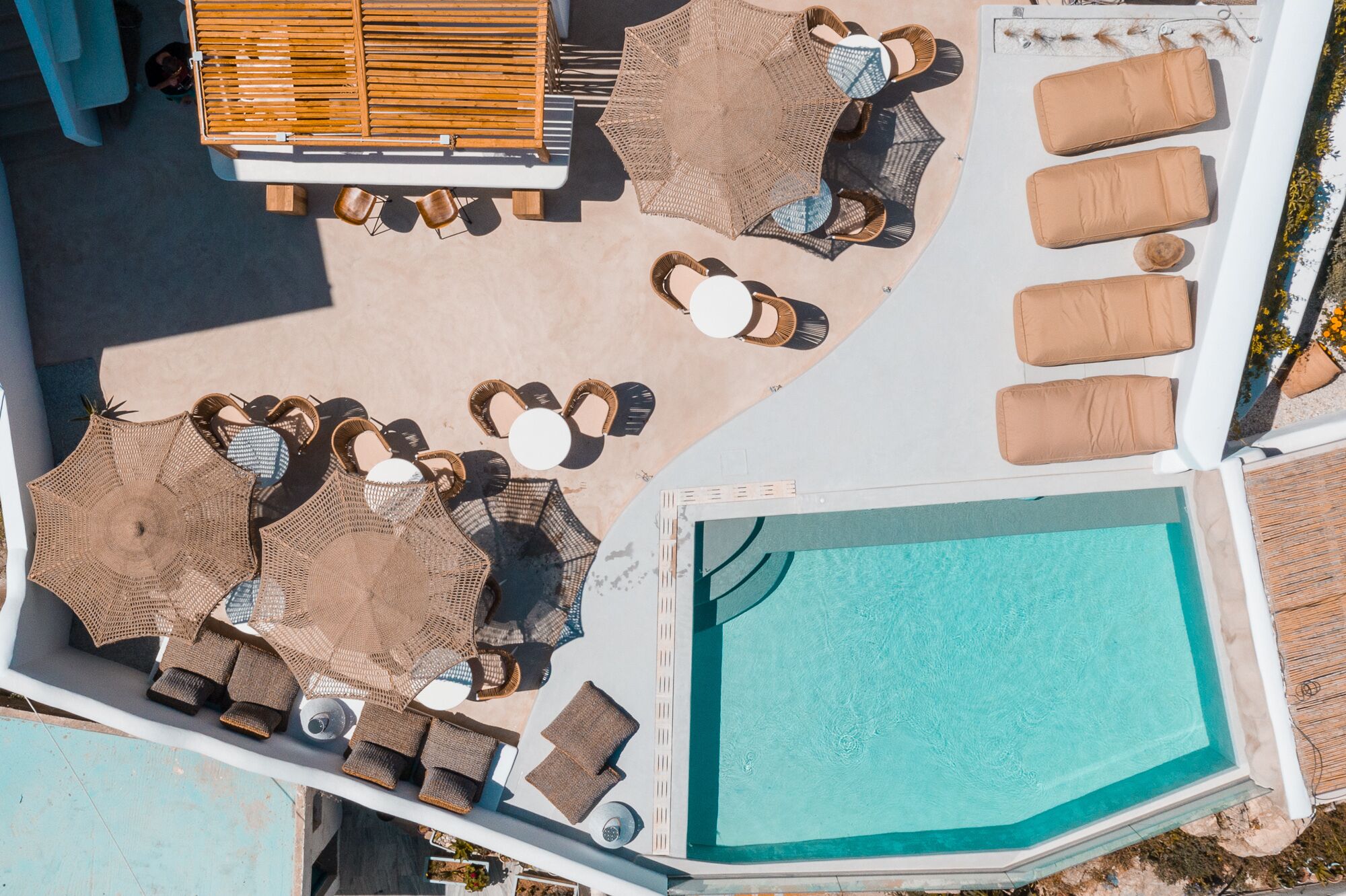 An aerial view of a poolside area with lounge chairs, a wooden bench, and a pool.