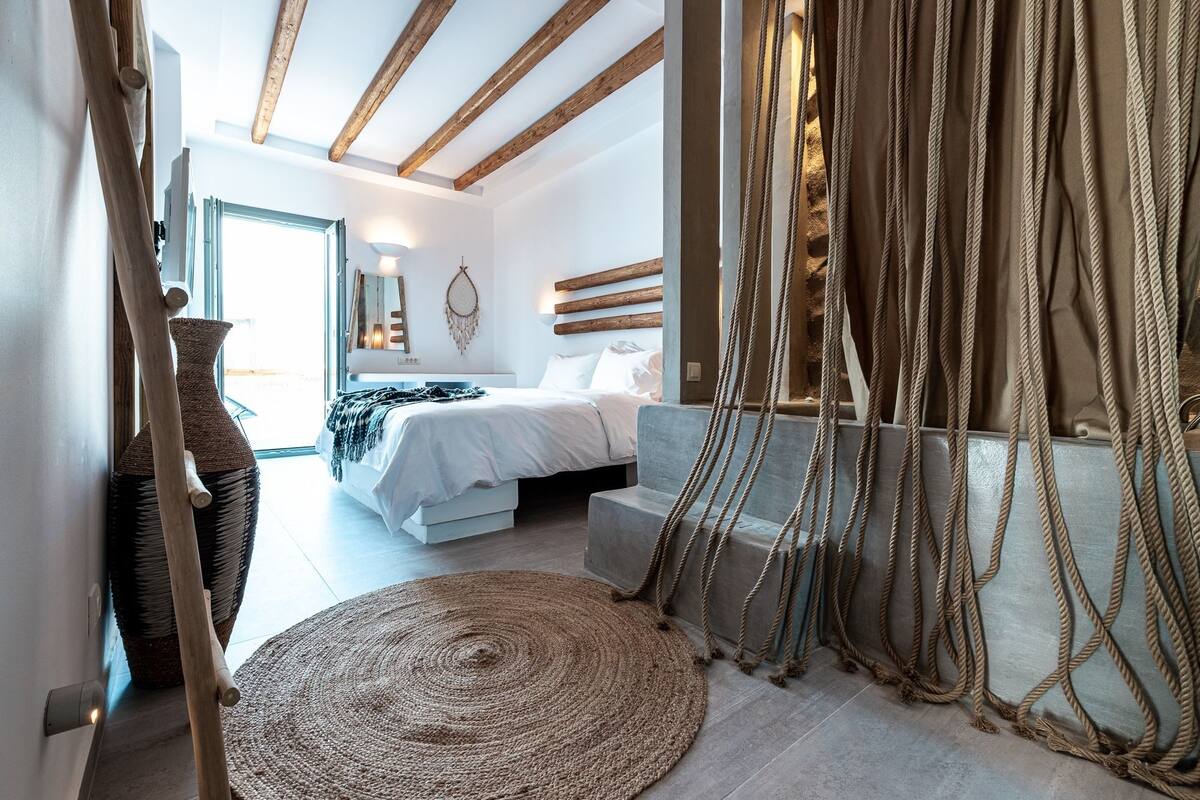 Ein modernes Schlafzimmer mit einem Bett, einem großen Spiegel und einem hängenden Schnürvorhang.