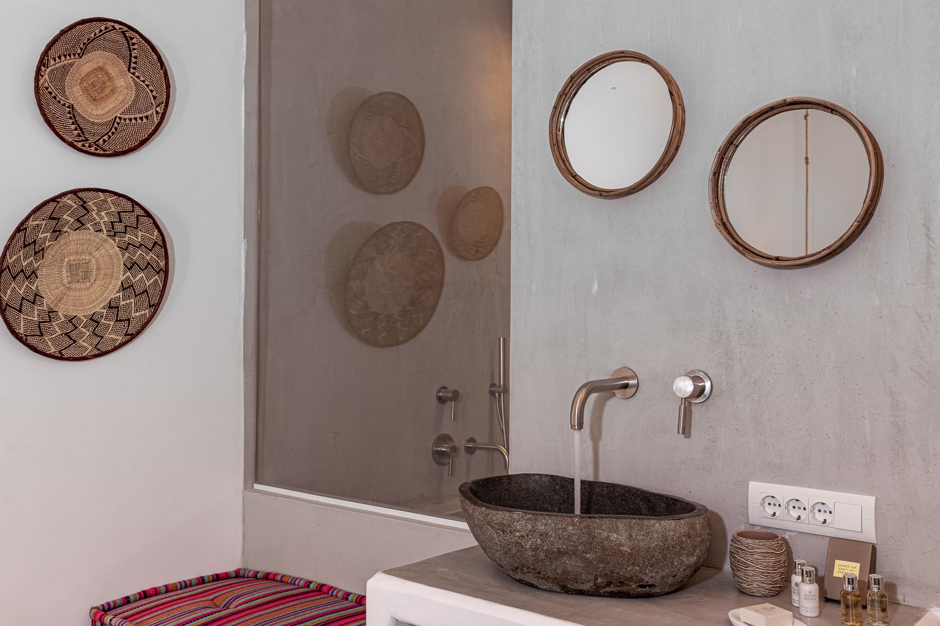 A bathroom with a stone sink, two wall-mounted mirrors, and a shower with a glass door.