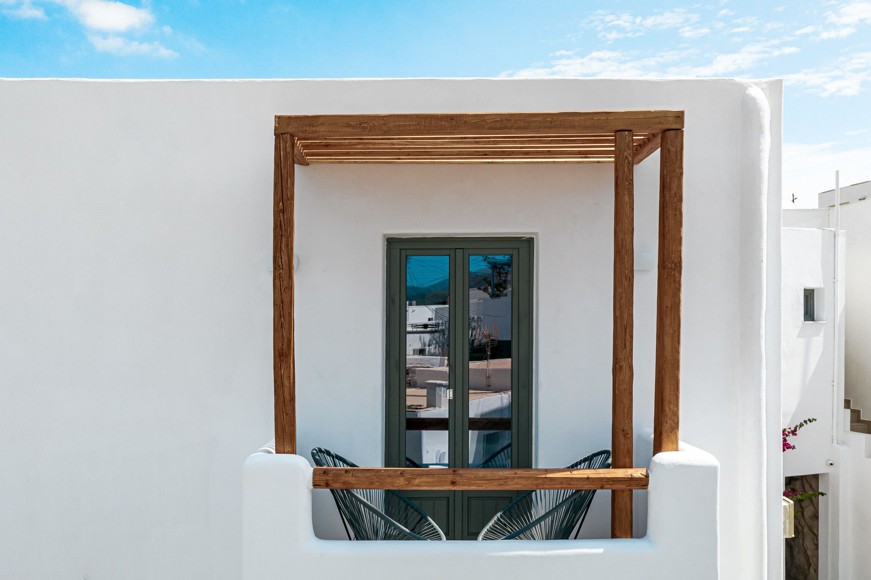 A white building with a wooden pergola and a window.