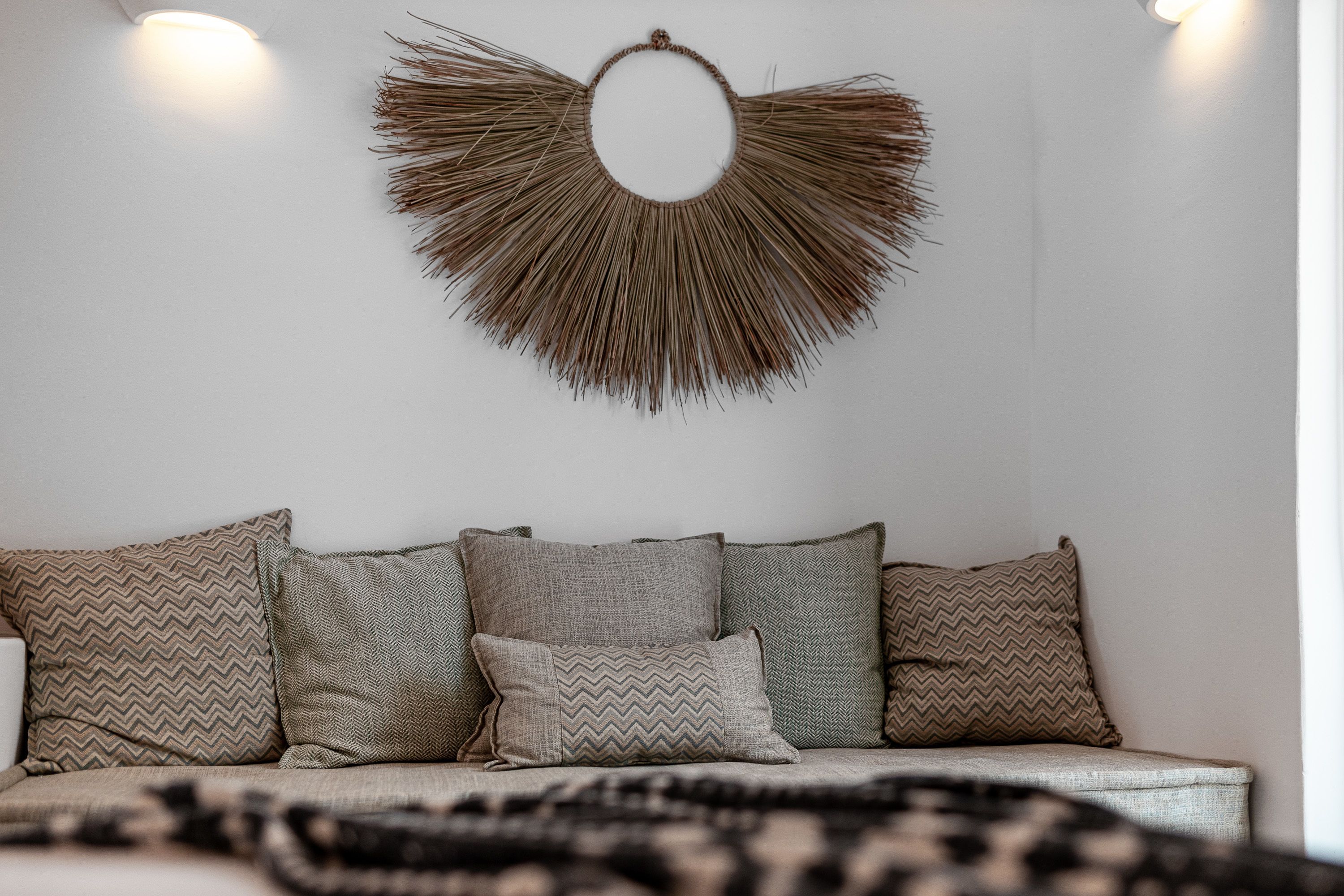 A modern living room with a sofa adorned with patterned cushions, a wall-mounted decorative piece, and a neutral color palette.