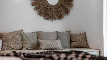 A modern living room with a sofa adorned with patterned cushions, a wall-mounted decorative piece, and a neutral color palette.