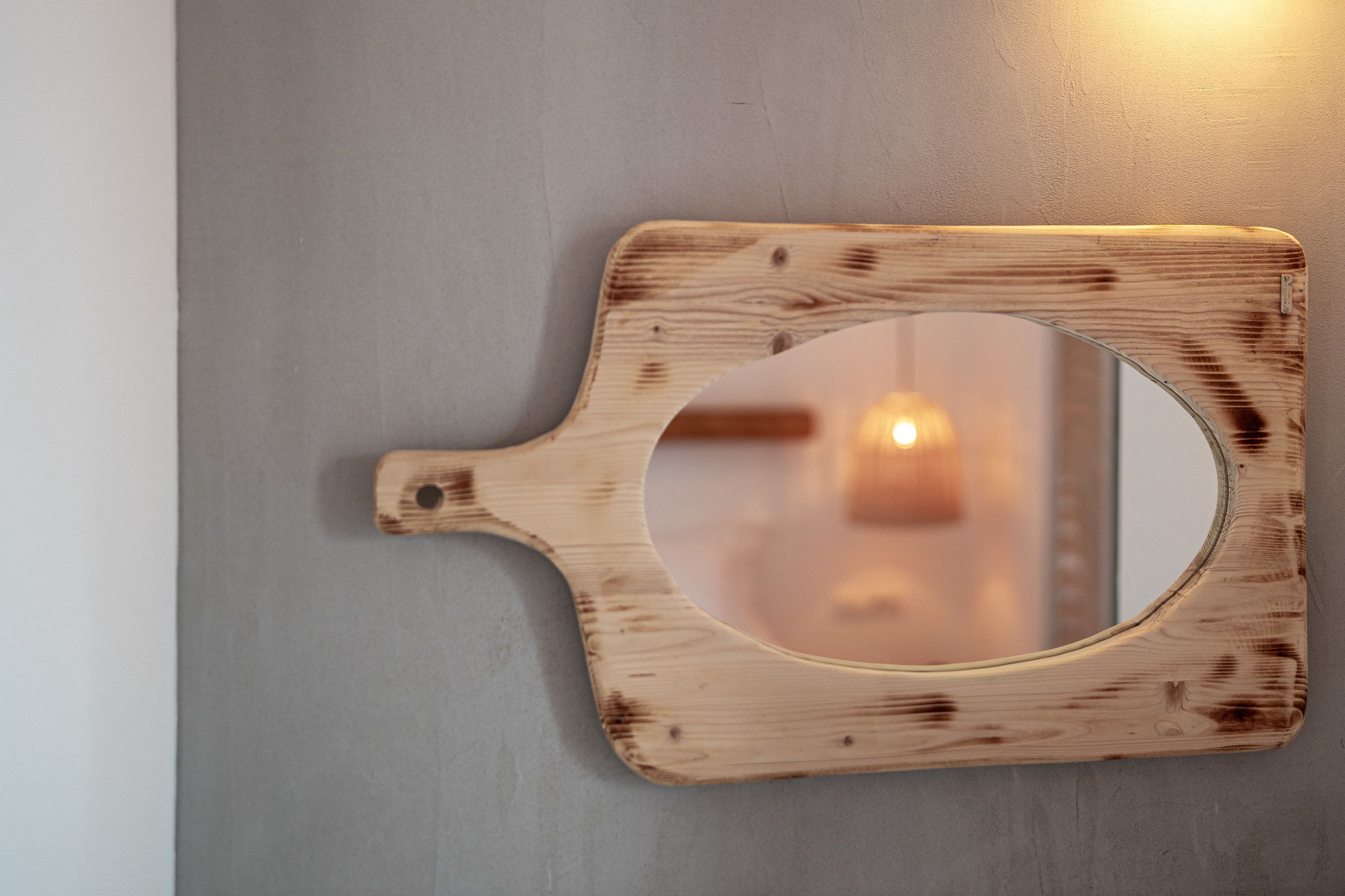 A wooden wall-mounted mirror with a circular center.