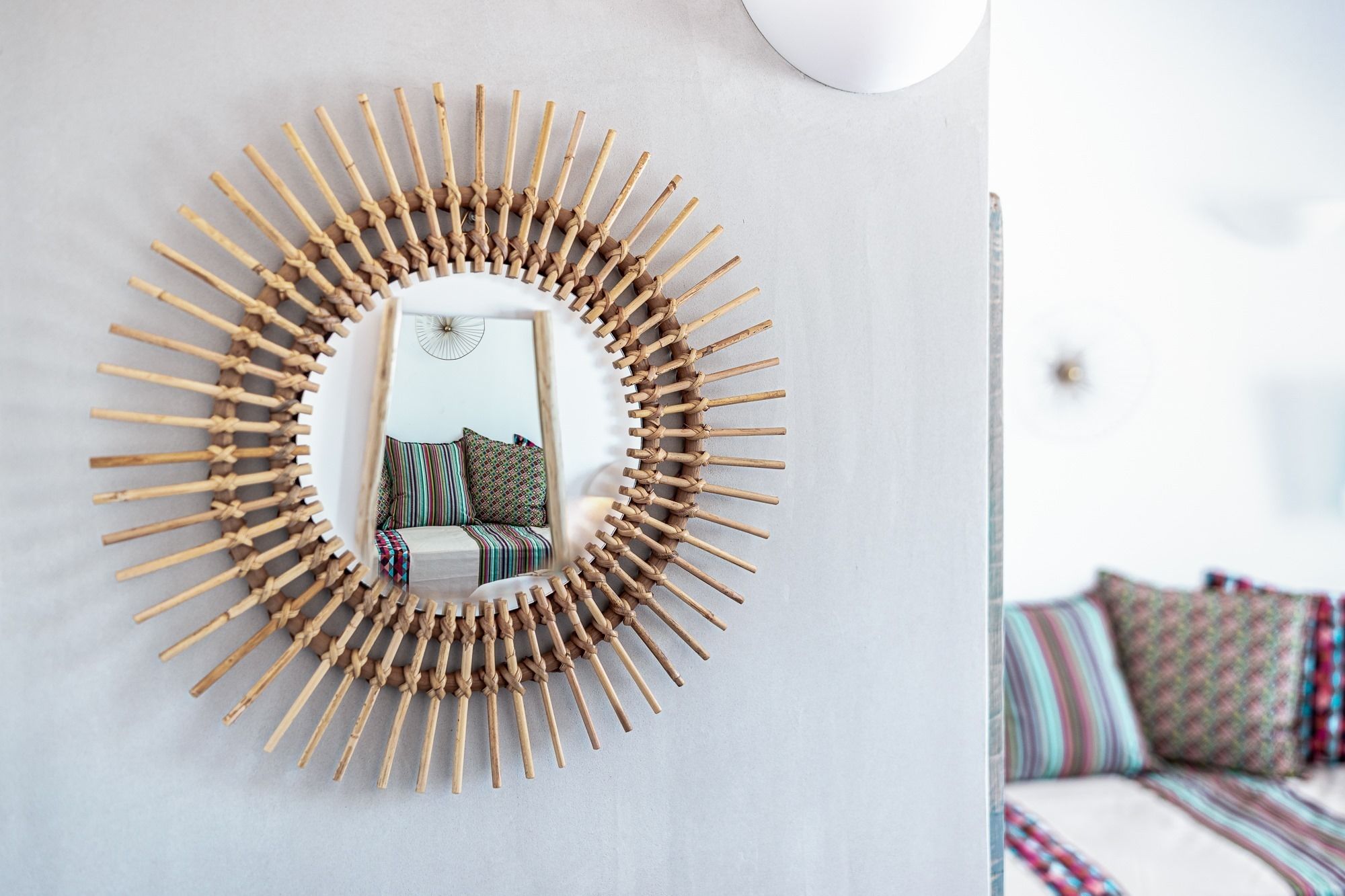 Un miroir rond, encadré de bambou, est accroché au mur.