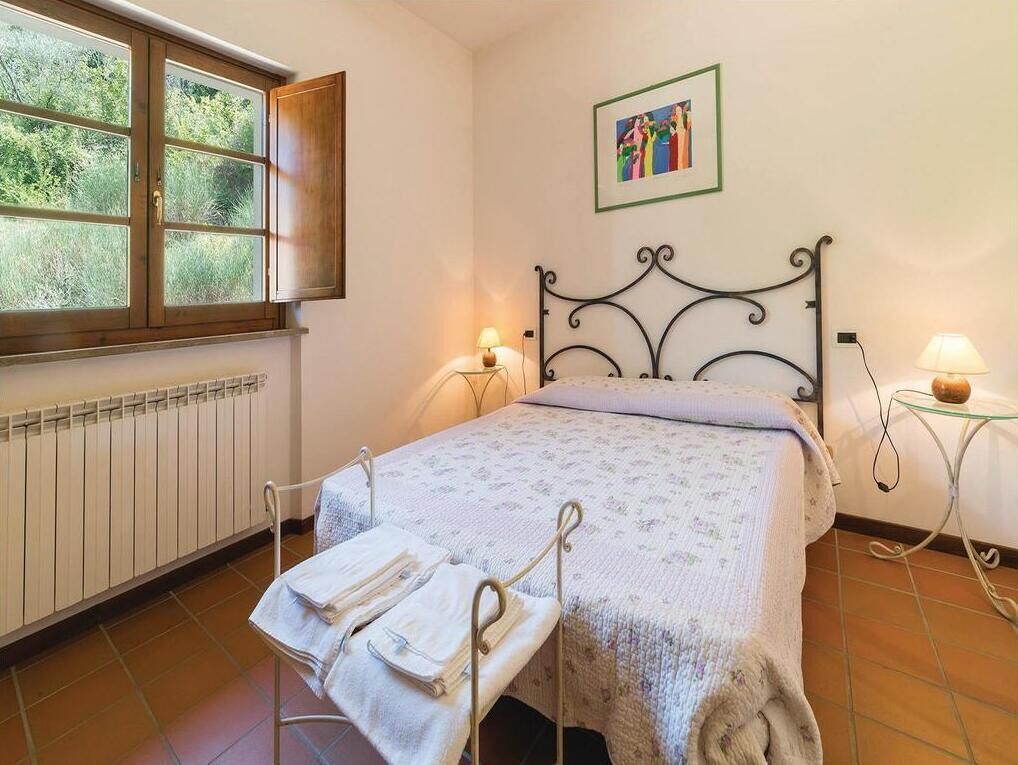A bedroom with a bed, a radiator, a window, and a picture on the wall.