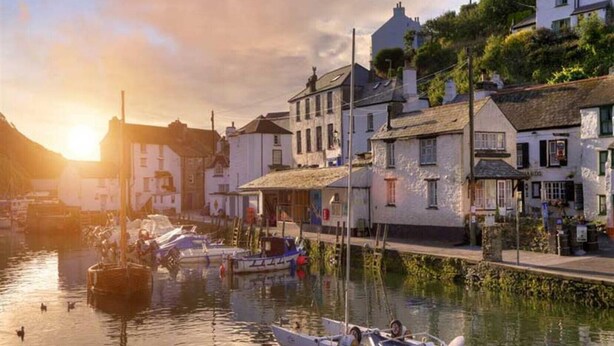 Une ville riveraine aux bâtiments traditionnels, avec un quai où sont amarrés des bateaux, et un coucher de soleil.
