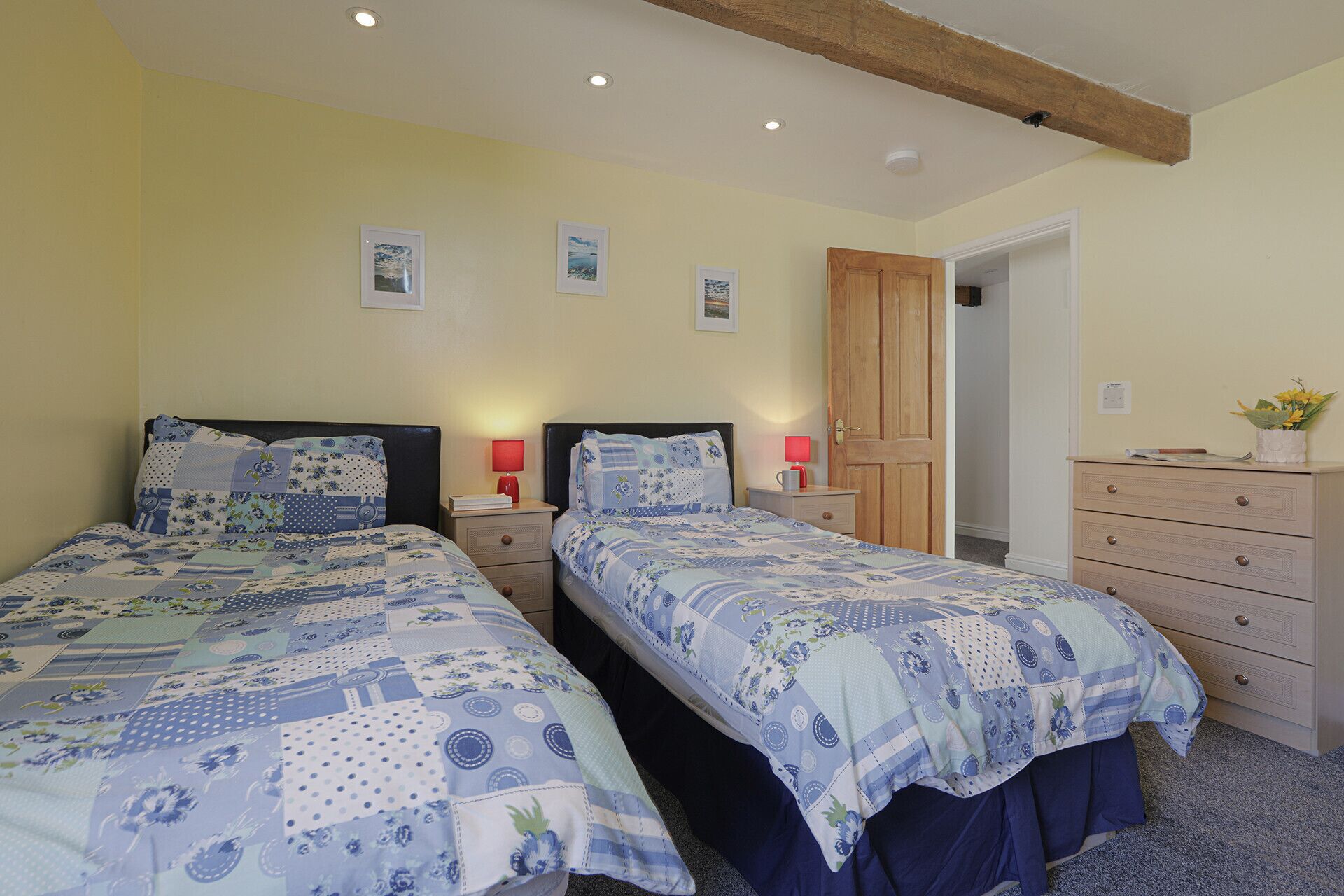 Une chambre avec deux lits, une armoire en bois et une porte donnant sur une autre pièce.