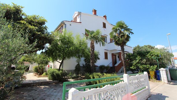 A white building with a balcony, surrounded by greenery and palm trees. - Apartments Olga (Rovinj)