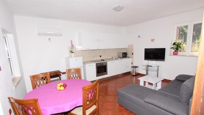 A compact living space with a dining area, kitchenette, and a gray sofa. - Apartments Olga (Rovinj)