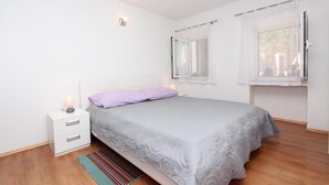 A bedroom with a bed, a nightstand, a lamp, and a window with curtains. - Apartments Olga (Rovinj)
