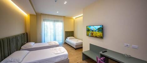 Een hotelkamer met twee bedden, een bureau, een stoel, een televisie en een raam met gordijnen.