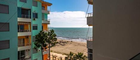 A multi-story building with balconies overlooking a beach.