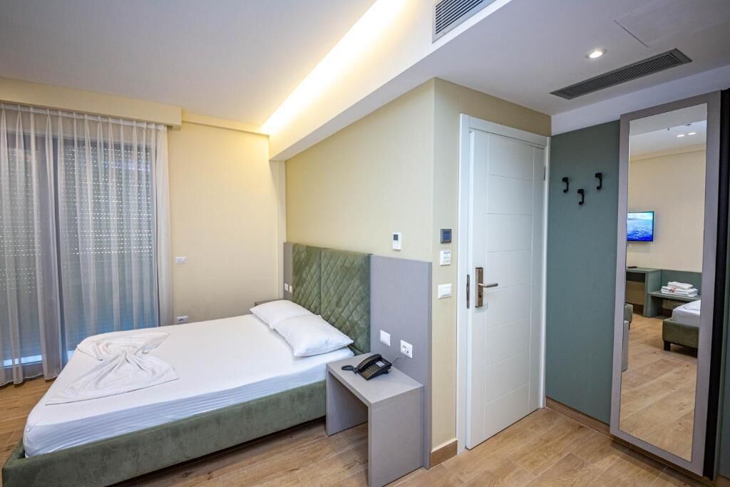 Una habitación de hotel con cama, mesita de noche y espejo.