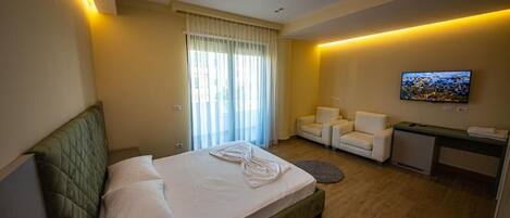 A hotel room with a bed, a desk, a chair, a TV, and a window with curtains.