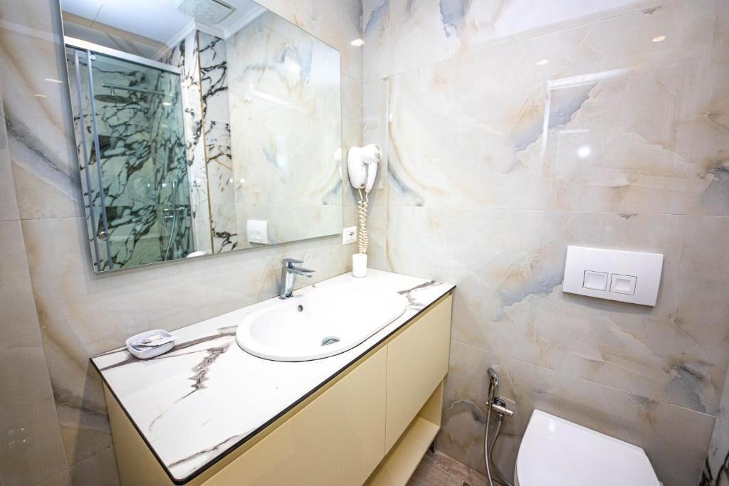 A bathroom with a marble sink, a glass shower enclosure, and a white toilet.