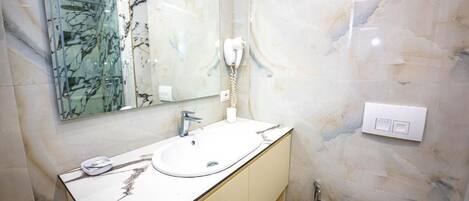 A bathroom with a marble sink, a glass shower enclosure, and a white toilet.