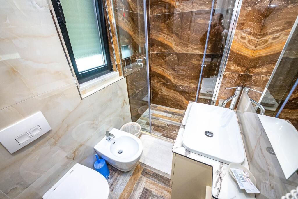 Une salle de bain moderne avec une douche à parois de verre, un lavabo blanc et un bidet.