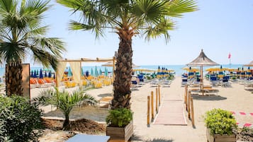 En privat strand, hvidt sand, liggestole, parasoller