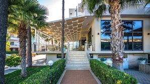 Un edificio moderno con una zona de estar cubierta al aire libre, una escalera central y jardines bien cuidados.