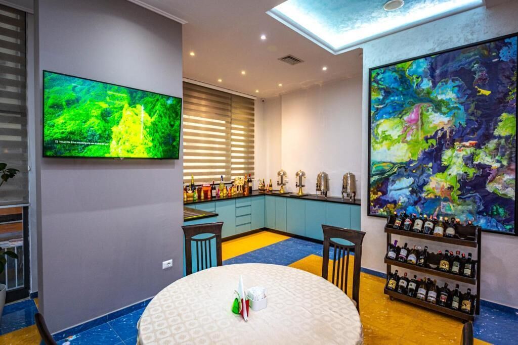 A modern kitchen with a large TV, a wine rack, and a colorful abstract painting.