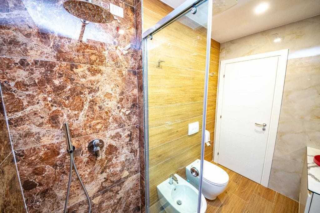 Un baño con ducha de vidrio, inodoro y lavamanos.