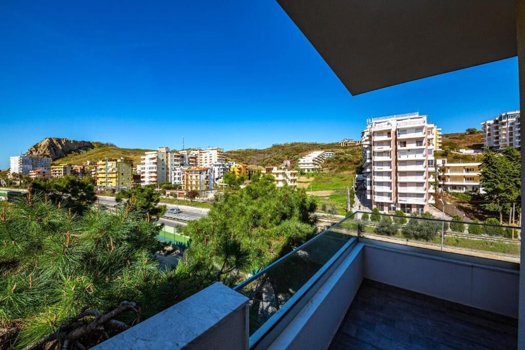 A balcony with a view of a residential area, including buildings and greenery.