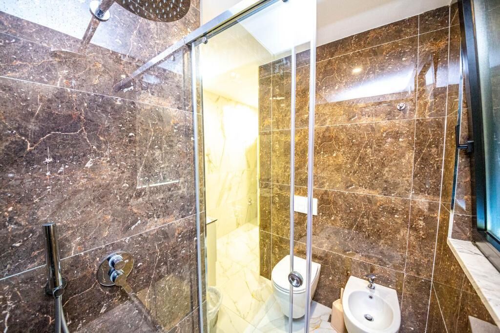 Ein modernes Badezimmer mit einer gläsernen Duschkabine, einer Toilette und einem Bidet.