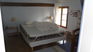 A bedroom with a bed, a nightstand, a lamp, a wooden chair, and a window with curtains. - 2 Beautiful country houses fully restored - stunning view                 (Dordogne)