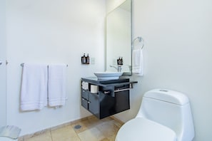 A modern bathroom with a white toilet, a black vanity with a large mirror, and two white towels hanging on the wall. - Capitalia | Stylish 2BR in Santa Fe’s Top Spot (Ciudad de México)