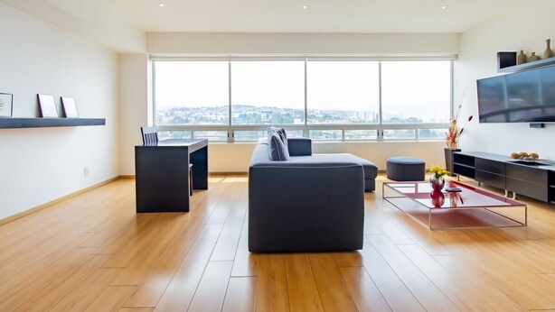 Un salon moderne avec une grande fenêtre, un canapé, une table basse et un téléviseur.