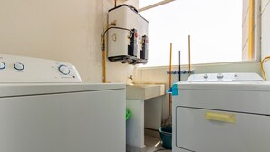 Une buanderie équipée de deux machines à laver, d’un chauffe-eau et d’une fenêtre.