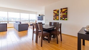 Un salon moderne avec un coin repas, de grandes fenêtres et une vue sur la ville.